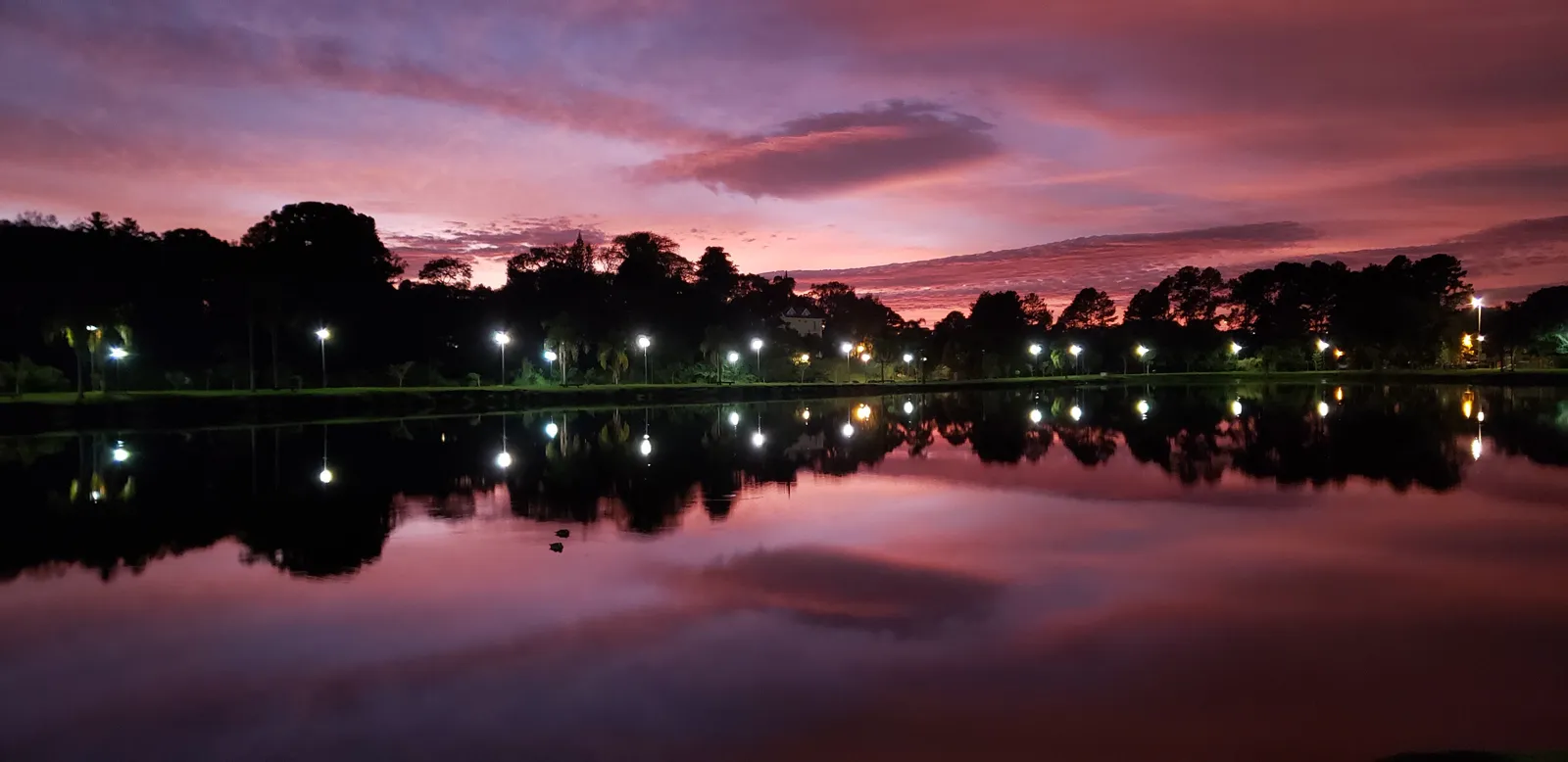 Amanhecer no Parque Bacacheri, com o lago refletindo o céu